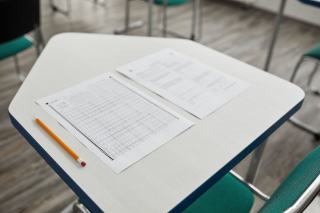Table d'examen avec copies et crayon dans une salle vide