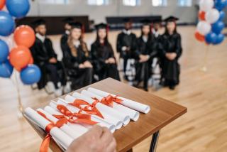 Diplômes roulés et noués posés sur un pupitre