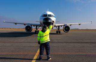 Placeur en gilet jaune qui guide un avion avec ses bâtons