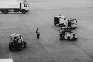 Agents et tracteurs à bagages sur l'aire de trafic, en noir et blanc