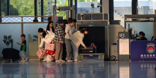 Passagers qui déposent leurs bagages au poste d'inspection filtrage